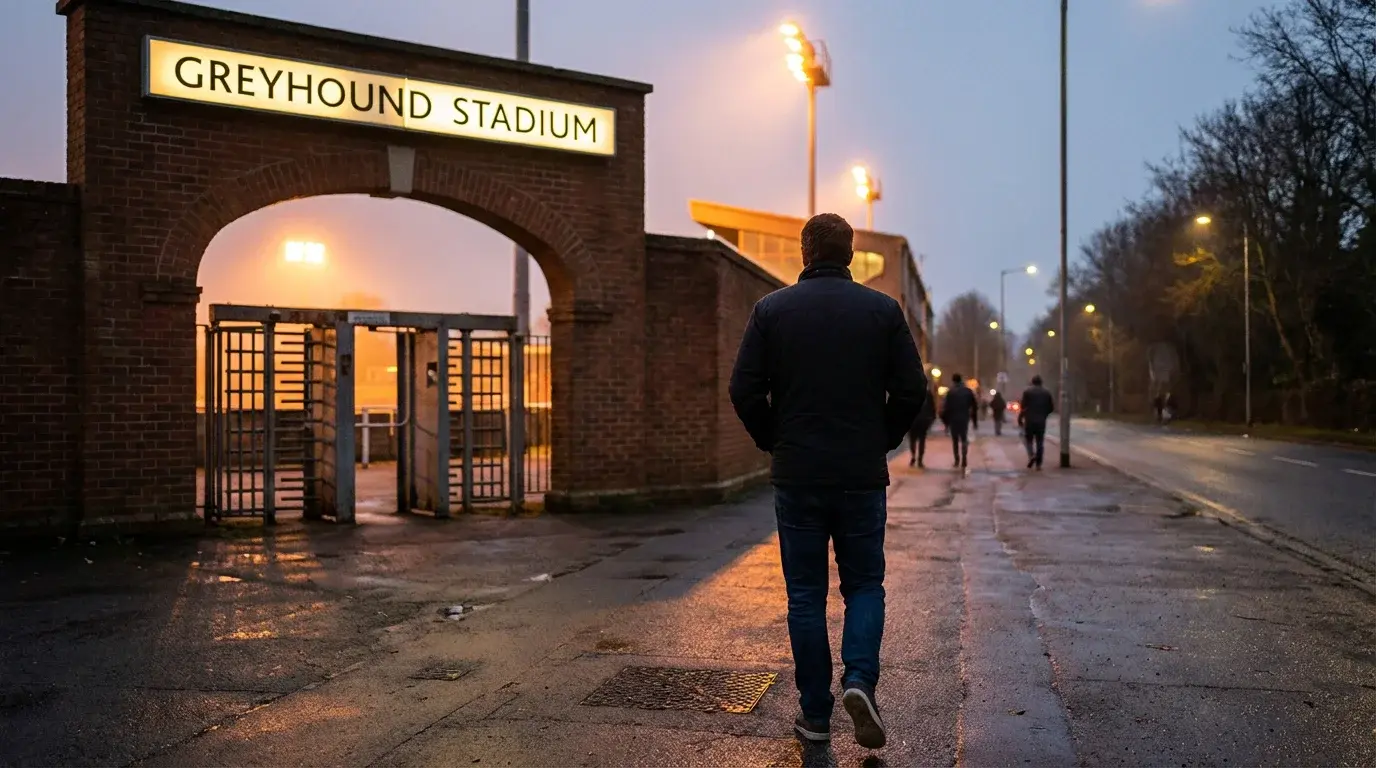 Person calmly leaving a UK greyhound stadium at the end of an evening meeting